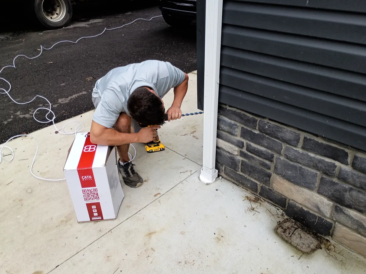An ODA installer running CAT6 cable and mounting a camera at a home